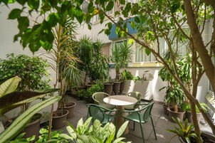 Ein Wintergarten mit Blumentöpfen, einem runden Tisch und grünen Stühlen.