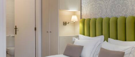 A hotel room with a bed, a nightstand, a wall-mounted lamp, and a patterned wallpaper.