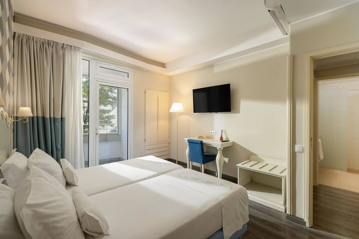 Ein Hotelzimmer mit einem Bett, einem Schreibtisch, einem Sessel, einem Fernseher und einer Tür.