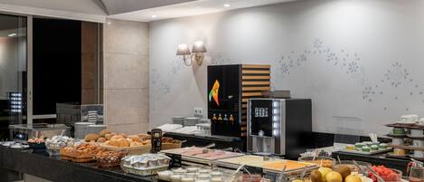 Un bufé con diversos alimentos, entre ellos frutas, pasteles y bebidas.