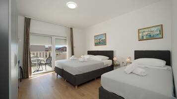 A hotel room with two beds, a balcony, and a painting on the wall.