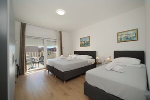 Habitación de hotel con dos camas, un balcón y un cuadro en la pared.