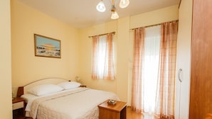 A bedroom with a bed, bedside table, nightstand, and a painting on the wall. - Adria (Kastela)