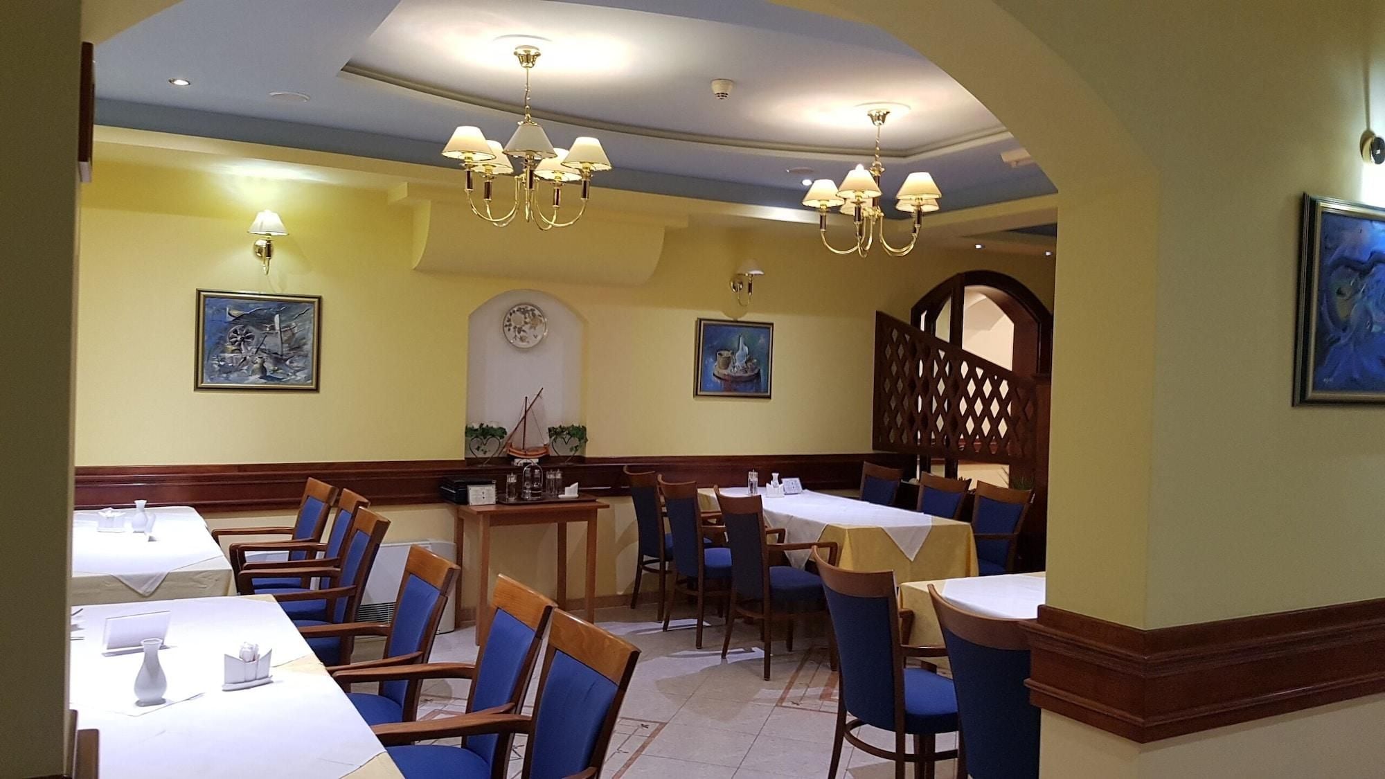 Un restaurante con varias mesas y sillas, candelabros y obras de arte en las paredes.