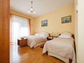 Une chambre d’hôtel avec deux lits, un parquet, un lustre et deux tableaux au mur.