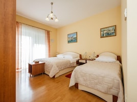 Una habitación de hotel con dos camas, pisos de madera, un candelabro y dos cuadros en la pared.