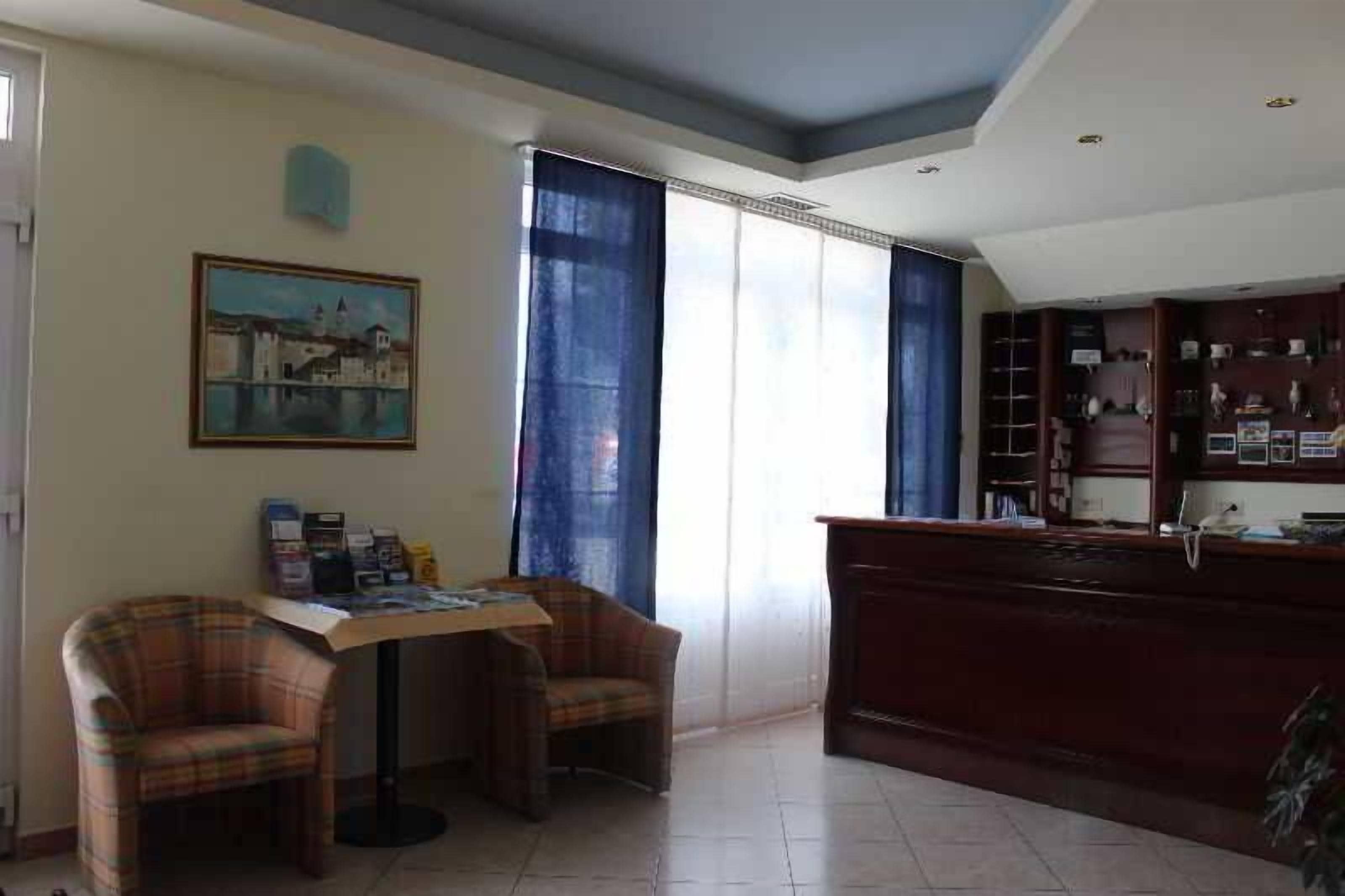 Una habitación con escritorio, dos sillas, un cuadro, una estantería y una ventana con cortinas.
