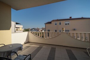A balcony with a table and chairs, a railing, and a view of neighboring buildings.