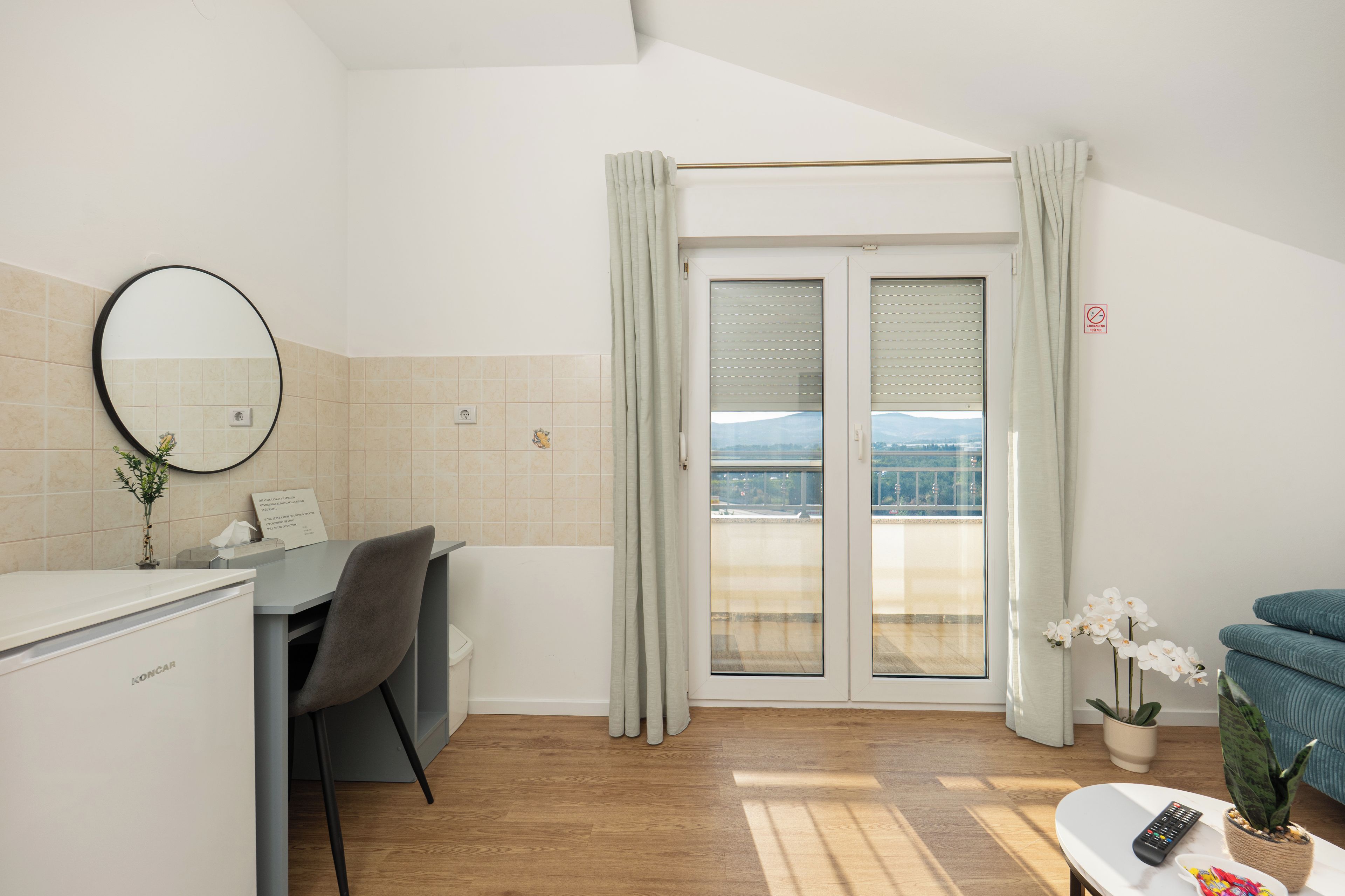 A hotel room with a desk, chair, and a view through the door.