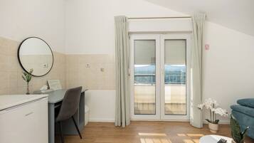 A hotel room with a desk, chair, and a view through the door.