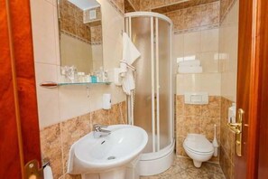 Baño con ducha, lavamanos, inodoro y espejo.