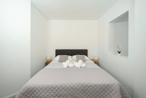 A hotel room with a bed, pillows, a nightstand, a lamp, and a small potted plant. - Adria (Kastela)