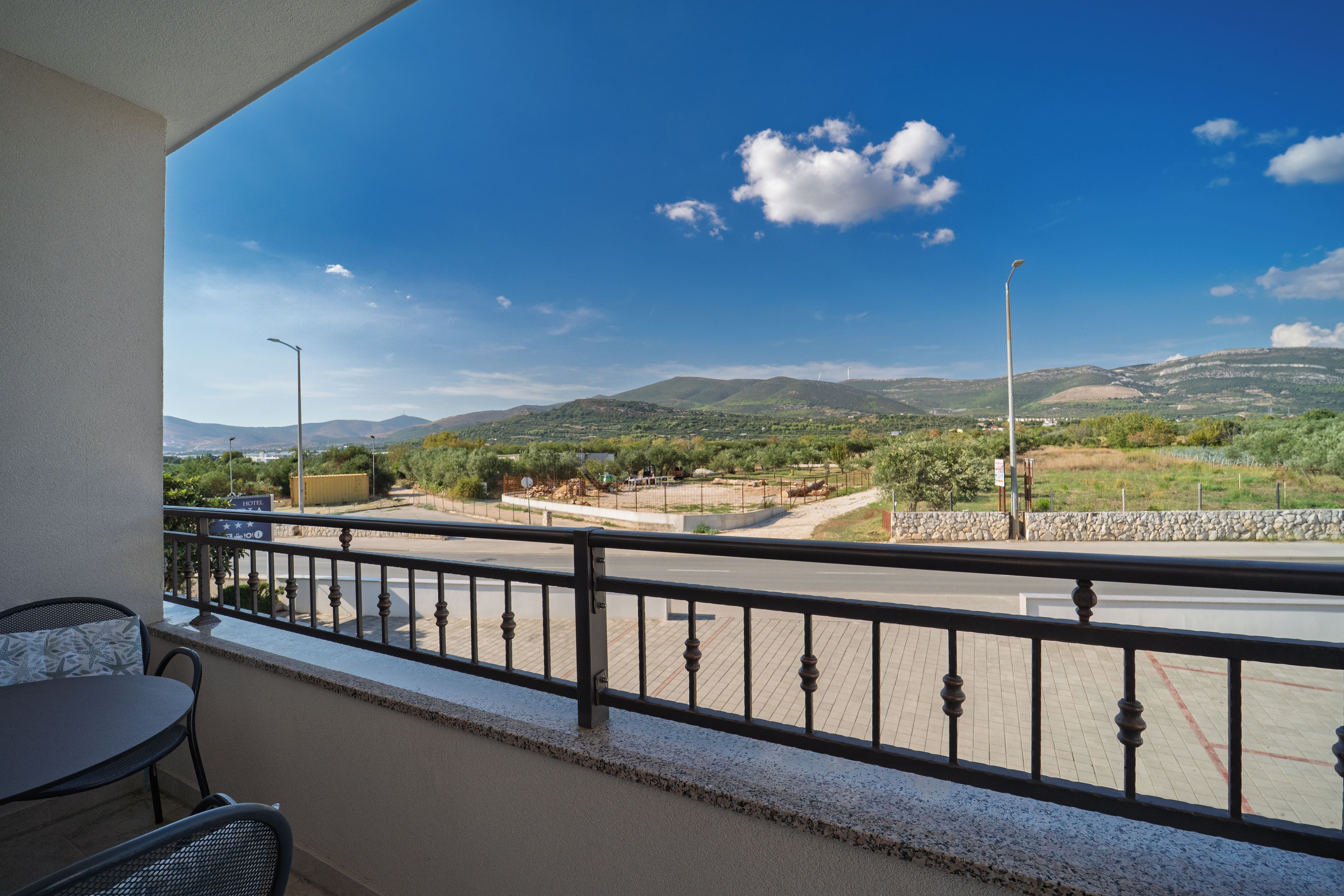 Ein Balkon mit Blick auf eine Straße, Berge und einen klaren Himmel.