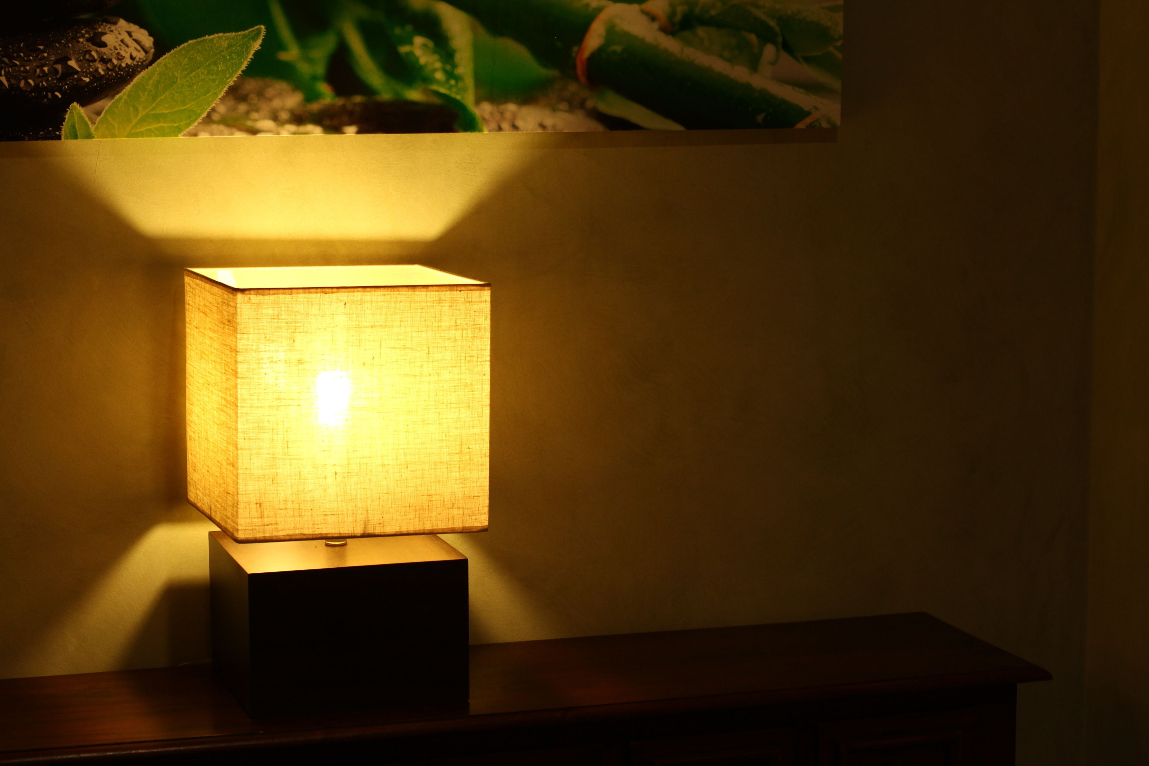 A square table lamp with a textured shade on a wooden table.