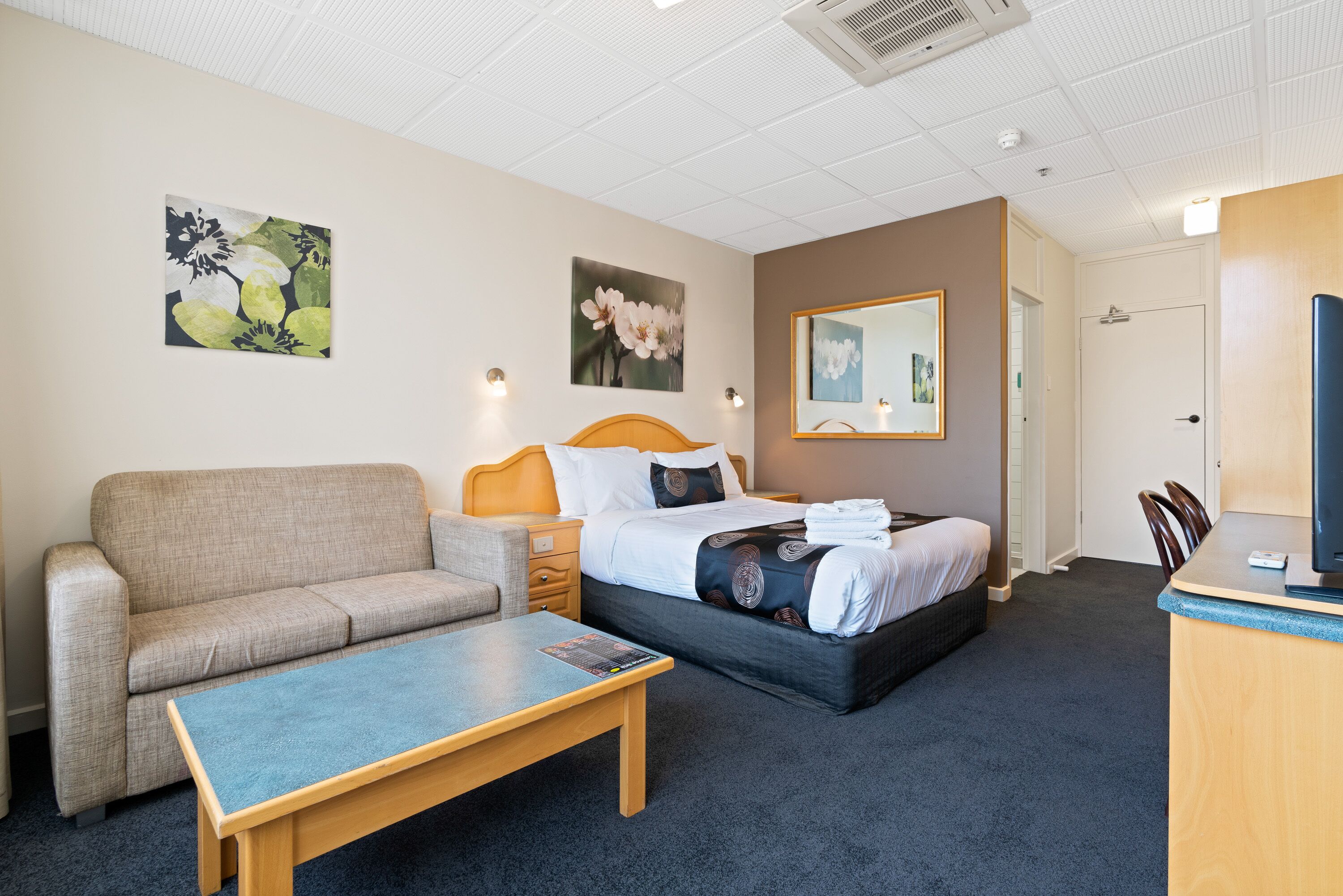 Une chambre d’hôtel avec un lit, un canapé, un bureau et des œuvres d’art accrochées aux murs.