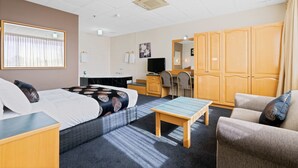 Une chambre d’hôtel comprenant un lit, un bureau, une chaise, un canapé et une armoire.
