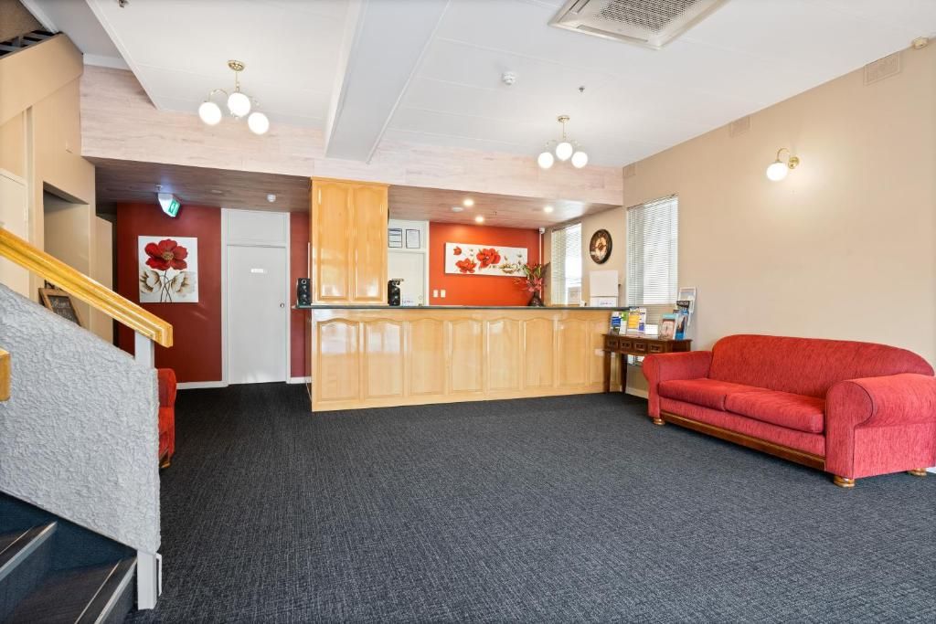 A hotel lobby with a reception desk, a red sofa, and a staircase.