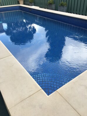 A rectangular swimming pool with a tiled edge and a surrounding light-colored deck. - Adelaide International Motel (Glenelg North)