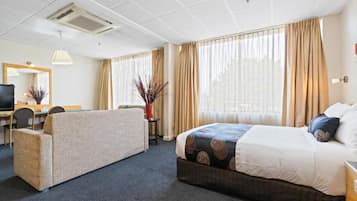 A hotel room with a bed, a sofa, a desk, and a television.