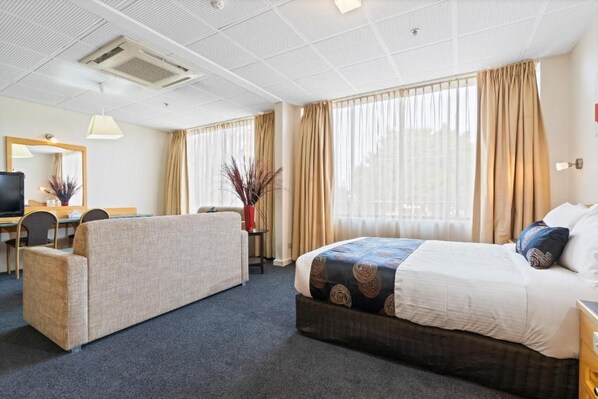 Habitación de hotel con cama, sofá, escritorio y televisor.