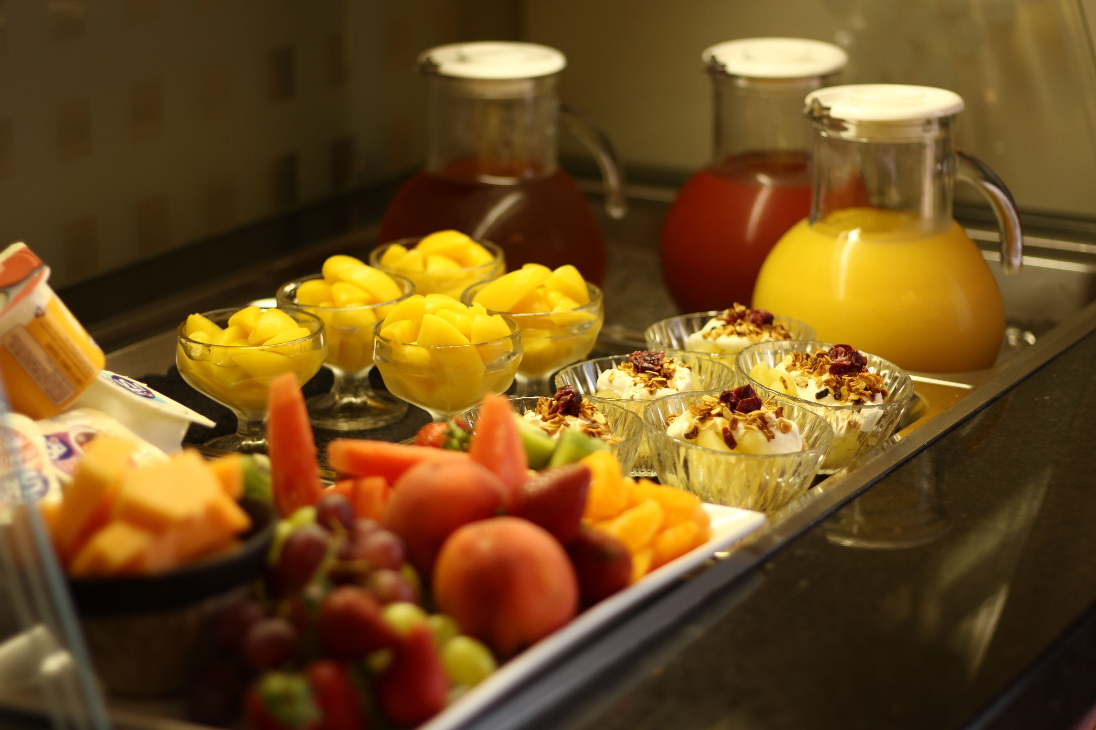 Un buffet de petit-déjeuner proposant une variété de fruits, des yaourts en couches et différentes boissons.