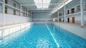 Ein Innenpool mit hoher Decke, mehreren Balkonen und Fliesenboden.