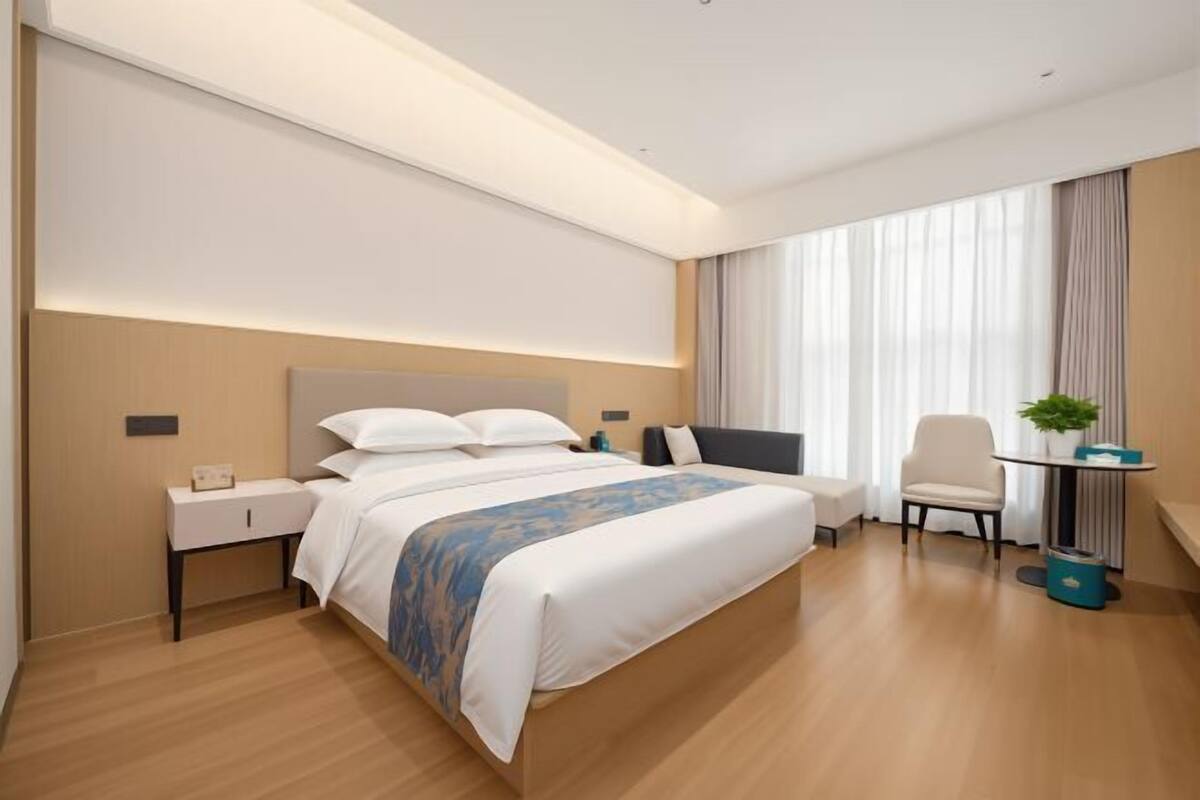 A modern hotel room with a large bed, bedside tables, a desk, and a chair.