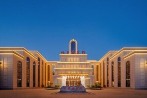 A grand hotel with a central arched entrance, multiple levels, and a symmetrical facade.