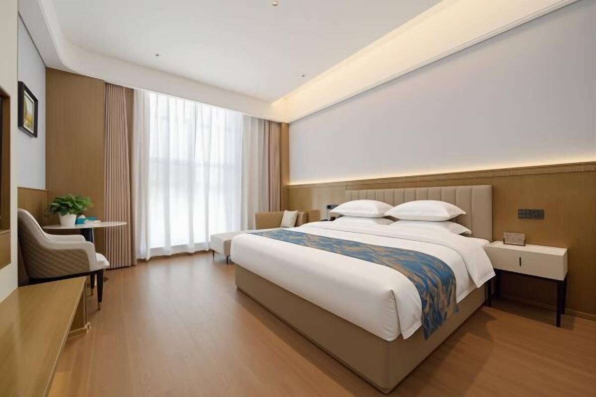 A hotel room with a large bed, bedside tables, a desk, and a chair.