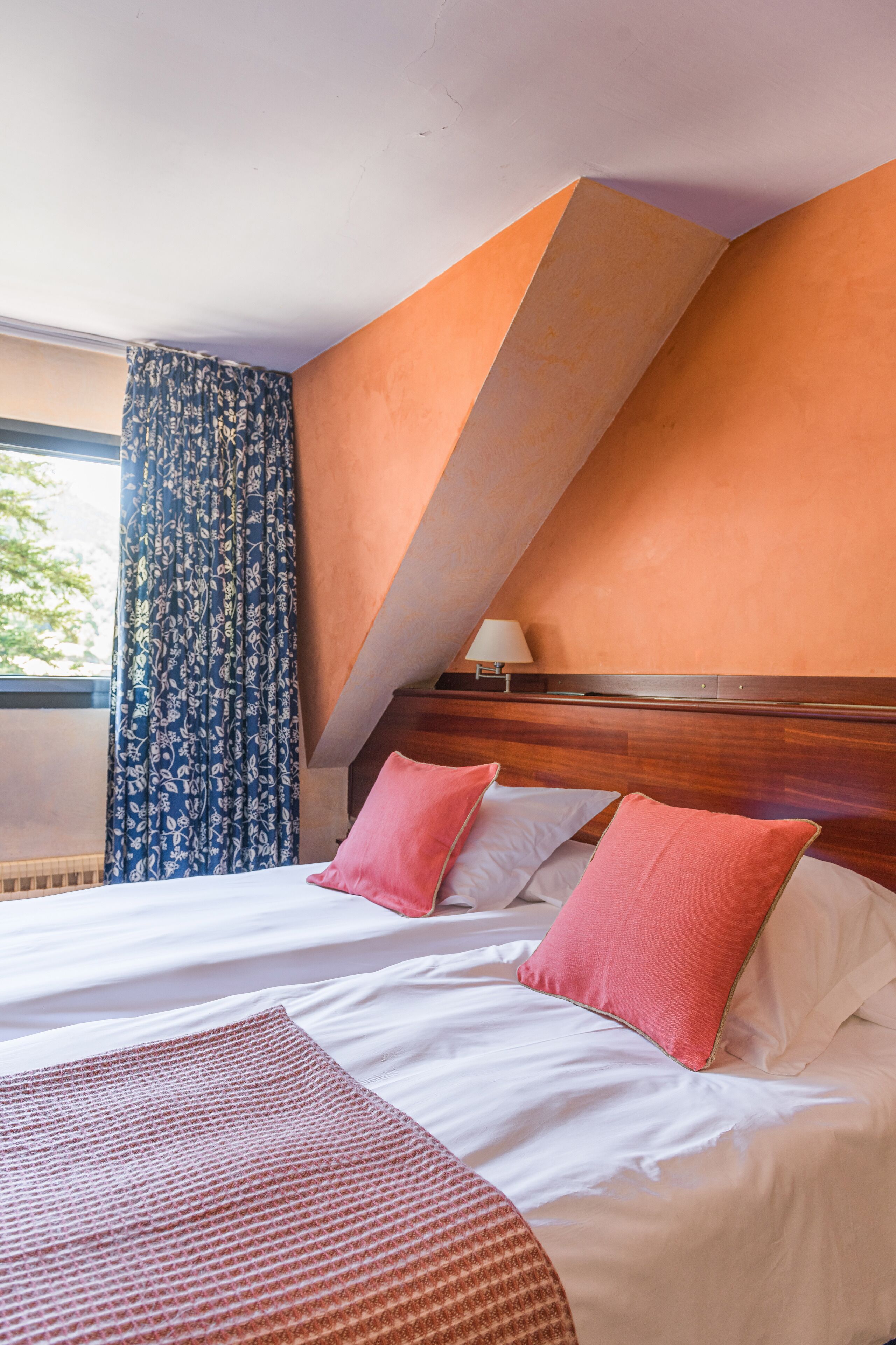 Een hotelkamer met een groot bed, een houten hoofdbord en een raam met gordijnen.