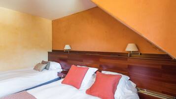 Una habitación de hotel con dos camas individuales, cabeceros de madera y techo inclinado.