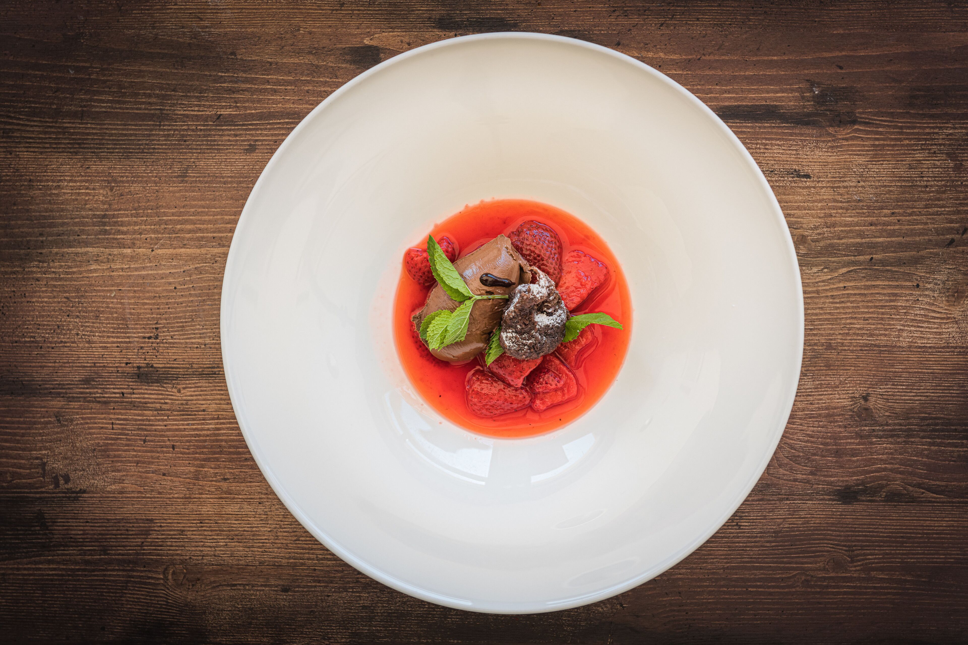 A white plate with a dessert on a wooden table.