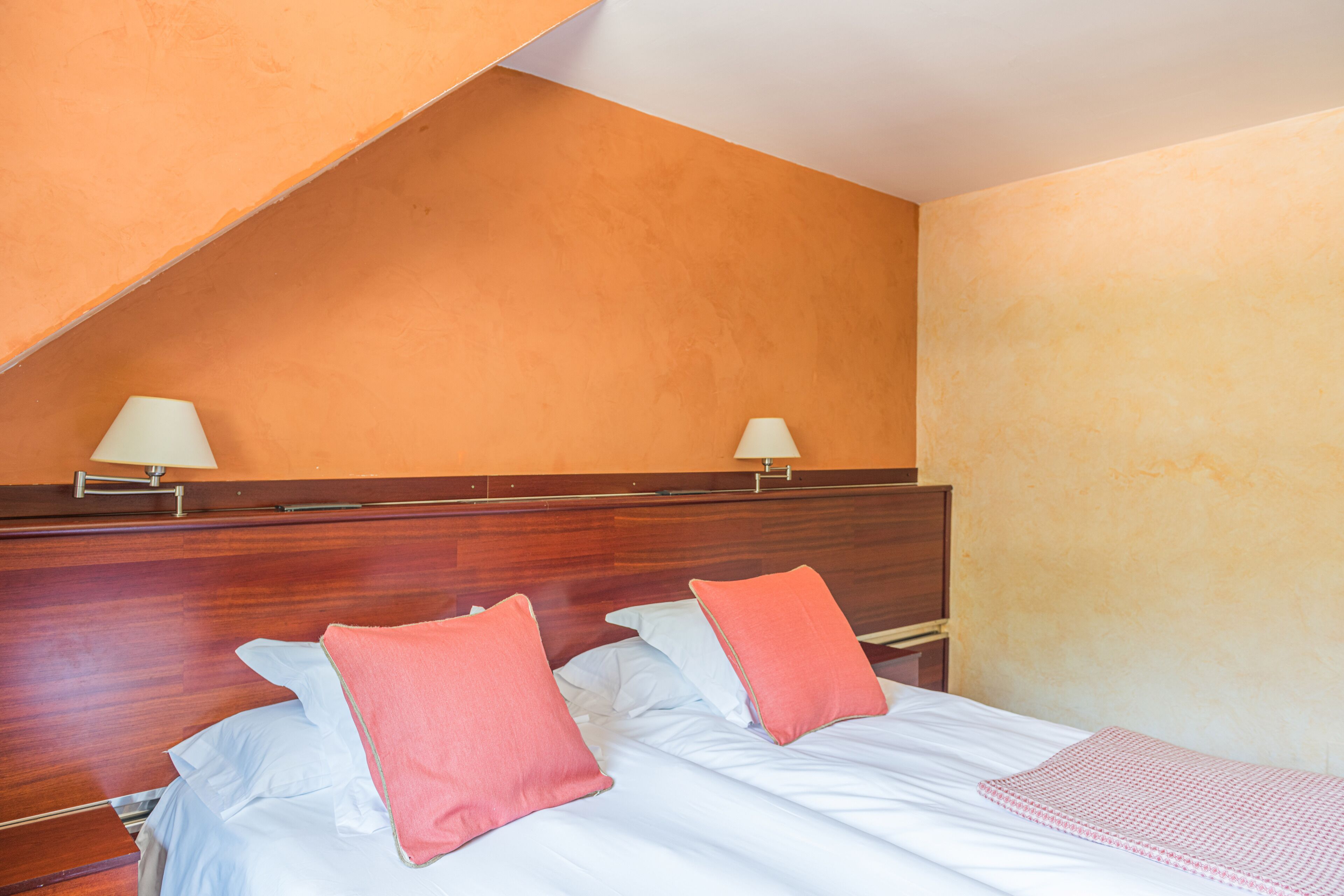 Habitación de hotel con dos camas, cada una con una almohada y una mesita de noche.