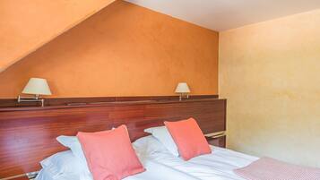 Habitación de hotel con dos camas, cada una con una almohada y una mesita de noche.