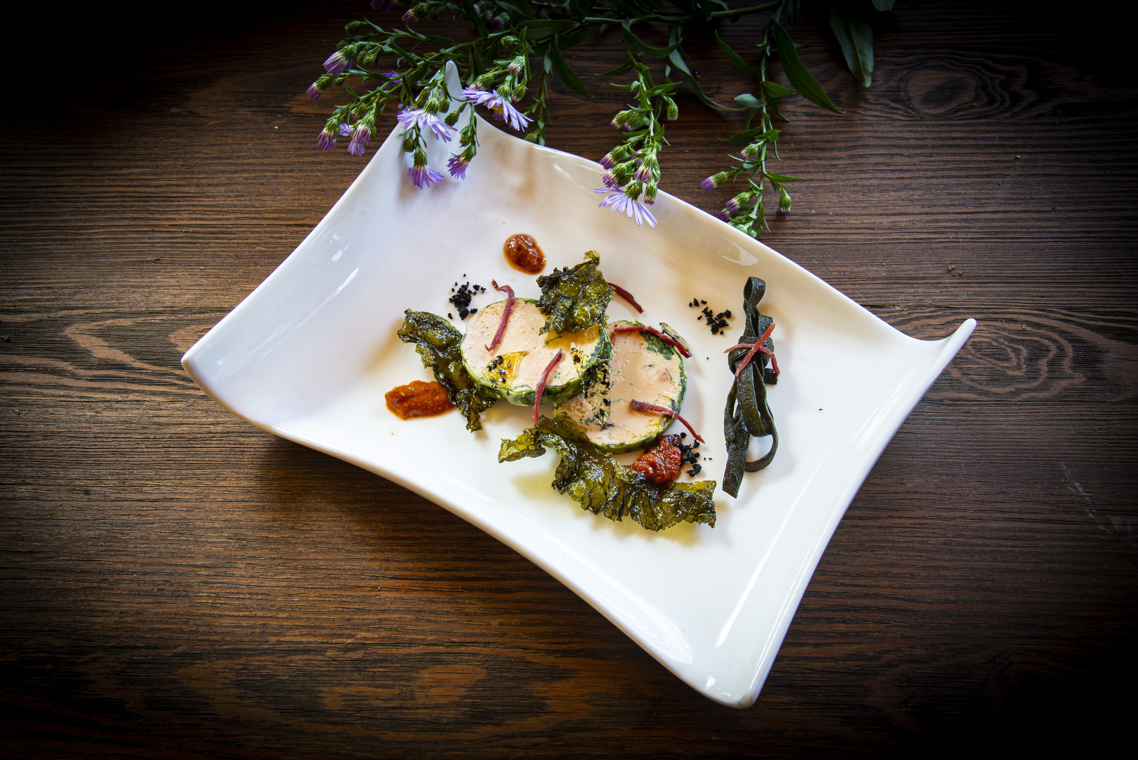 A white plate with a salad on a wooden table.