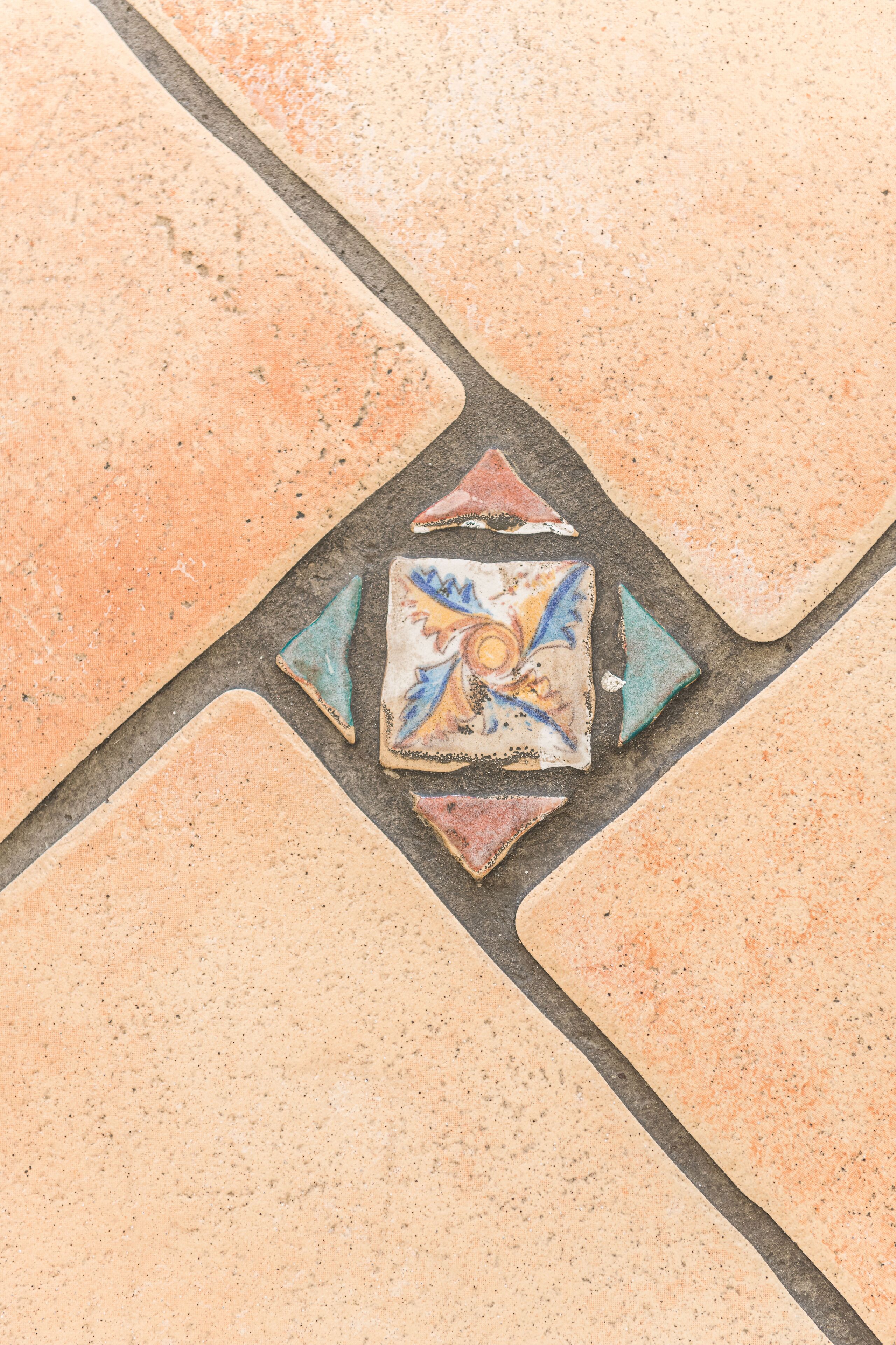 A patterned tile floor with a central decorative tile featuring a geometric design.