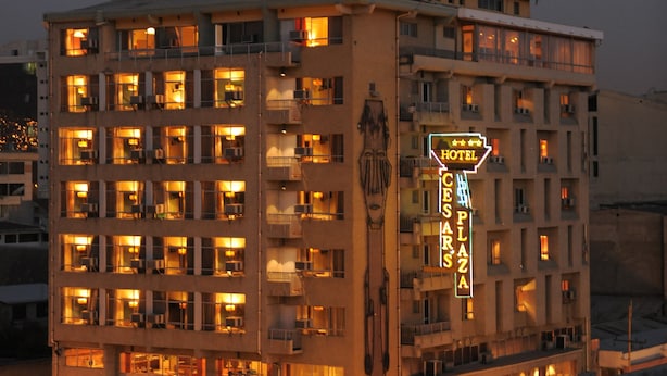 A multi-story hotel with illuminated signage, balconies, and a central plaza area. - Cesars Plaza Hotel (Cochabamba)