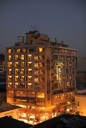 Un hotel de varios pisos con señalización iluminada, balcones y una plaza central.