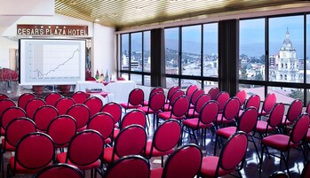 Un salón de conferencias con sillas rojas y una pantalla de proyecciones en el Hotel Cesar's Plaza.