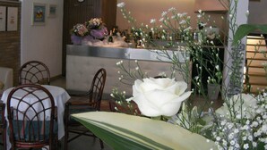 A reception area with a counter, chairs, and a large white flower arrangement. - Hotel Pinocchio (Cattolica)