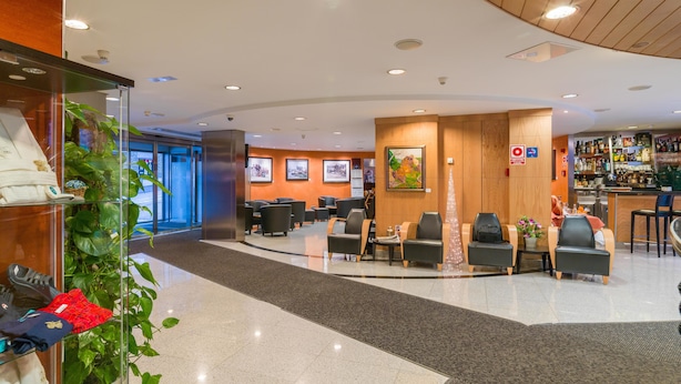 A hotel lobby with seating areas, a reception desk, and a bar.