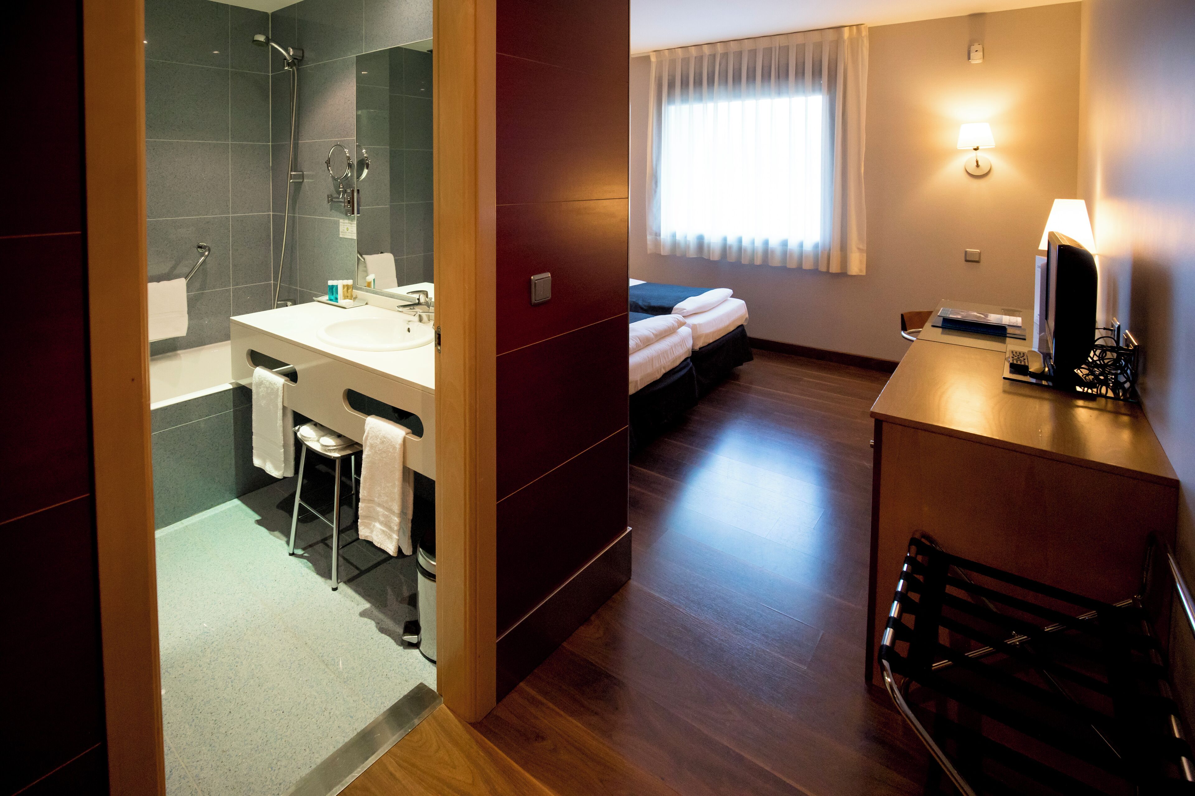 Une chambre d’hôtel moderne équipée d’une douche, d’un lavabo et d’un lit.