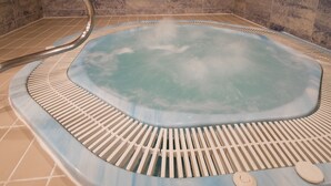 A hot tub with a tiled floor and a metal ladder.