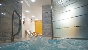 A hot tub with water jets, a wooden chair, and a glass partition.