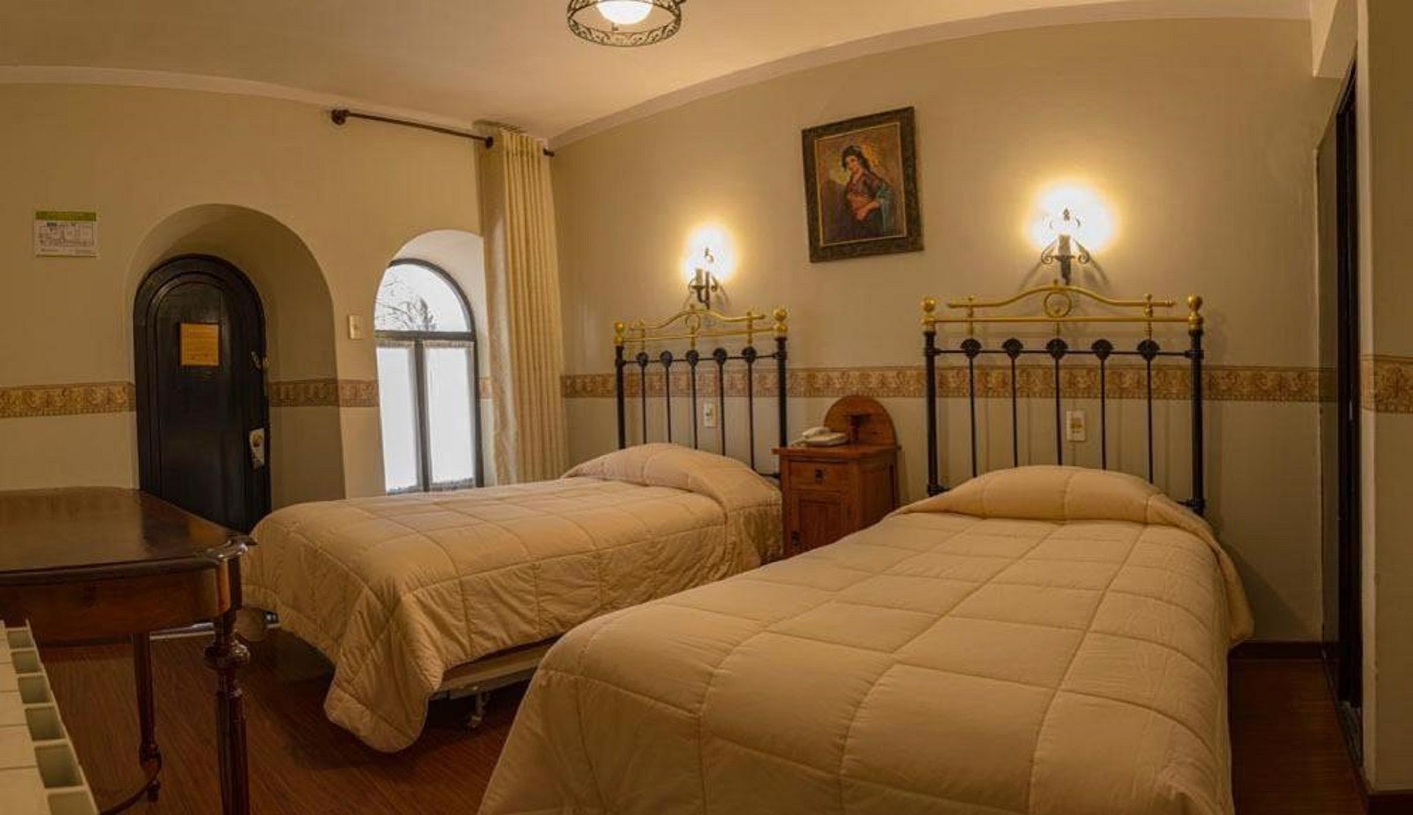 Ein Hotelzimmer mit zwei Betten, einem Klavier, einer Tür und einem Bild an der Wand.