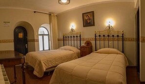 A hotel room with two beds, a piano, a door, and a painting on the wall. - Colonial Hostal (Potosi)