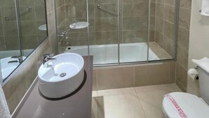 A modern bathroom with a glass-enclosed shower, a white sink, and a toilet. - Colonial Hostal (Potosi)