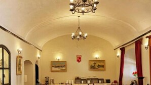 A dining area with round tables, chairs, a chandelier, and a wooden floor. - Colonial Hostal (Potosi)