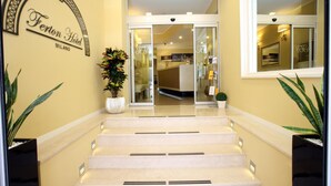 A hotel entrance with a staircase leading to a reception area. - Hotel Ferton (Milan)
