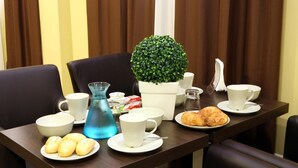 A breakfast table with plates of pastries, a blue water bottle, and a potted plant. - Hotel Ferton (Milan)